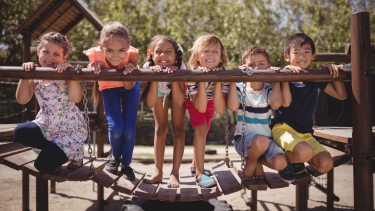 Children posing on a playground wooden bridge