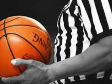 Referee holding an orange basketball, black background
