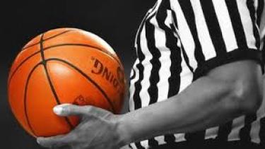 Referee holding an orange basketball, black background