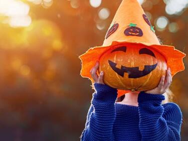 child wearing an orange pumpkin head