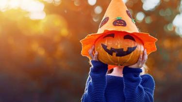 child wearing an orange pumpkin head
