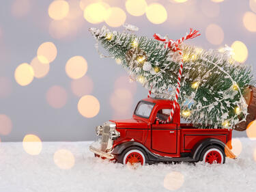 Christmas scene with a t old red pick up truck toy with a christmas tree toy on fake snow, 