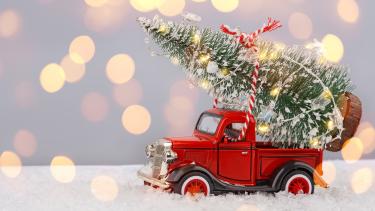 Christmas scene with a t old red pick up truck toy with a christmas tree toy on fake snow, 