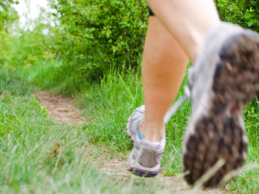 snap shot of feet wearing runners on a green grass outdoor path