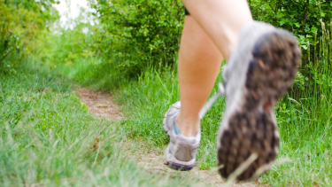 snap shot of feet wearing runners on a green grass outdoor path