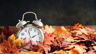 clock on a pile of fall coloured leaves 