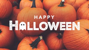 Happy Halloween in white letters on a pile of orange medium sized pumpkins