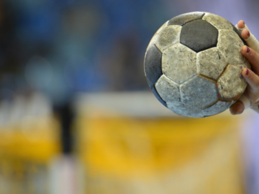 Handball, picture of a hand holding a ball, blurry background