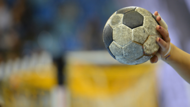 Handball, picture of a hand holding a ball, blurry background