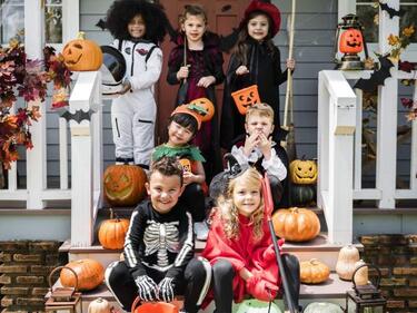 kids sitting on a white patio/steps wearing costumes
