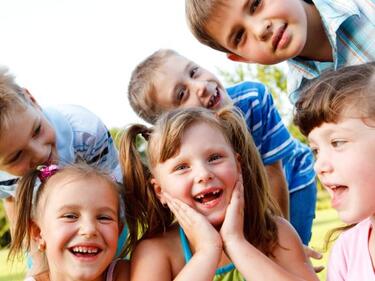 variety of small kids huddled together smiling
