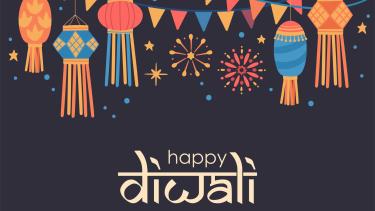 Happy Diwali in white on black background with colourful decorations and fireworks at the top
