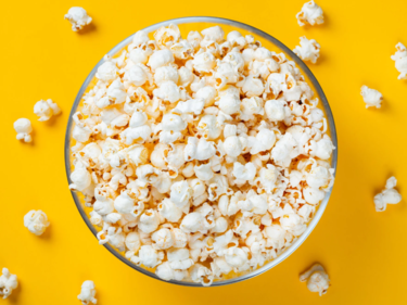 Bowl of popcorn birds eye view in glass bowl on a yellow background
