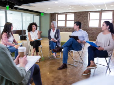 adults sitting in a circle on chairs talking