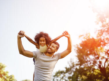 A dad holding a child on his shoulders