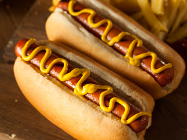 Two Hotdogs in buns with mustard swirled on top