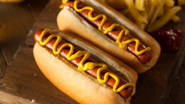 Two Hotdogs in buns with mustard swirled on top