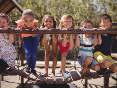 Children posing on a playground wooden bridge