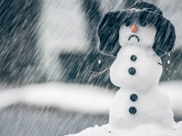 A snowman with a black bucket hat with sleet coming down around it  it