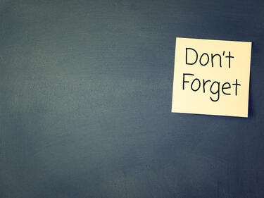 Chalk board with yellow sticky note "Don't Forget"