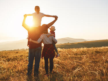 Family at sunset on a golden field looking out toward mountain range
