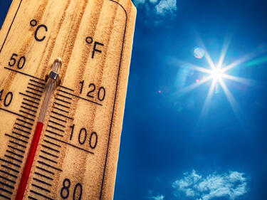 Hot Summer Day shown by wooden thermometer against blue sunny sky