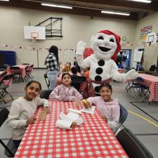Students eating treats in school gym at with Bonhomme