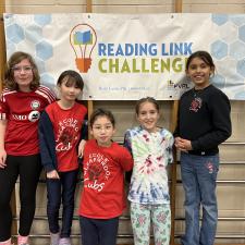 Students who participated in the Reading Link Challenge in front of sign