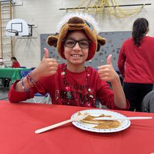 Student Enjoying Pancakes for Carnaval de Quebec in school gym in lumberjack clothing
