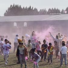 School wide holi celebration with teachers and students throwing holi powder on school field